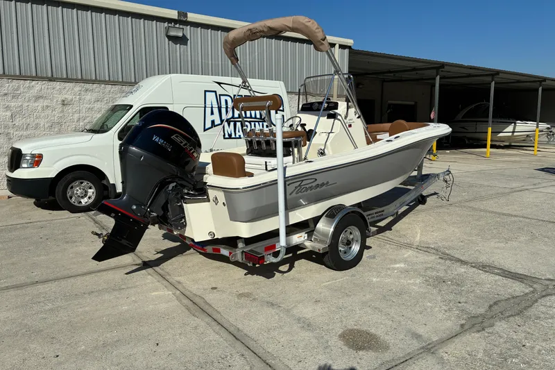 Slide: The Image of 2026 Pioneer 180 Islander boat on trailer, parked near a marine service van. - 1
