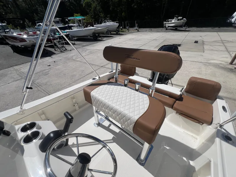 Slide: The Image of 2026 Pioneer 180 Islander boat interior with brown and white seating, steering wheel, and cup holders. - 13