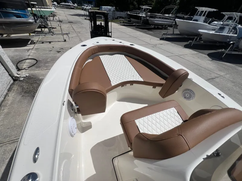 Slide: The Image of 2026 Pioneer 180 Islander boat interior with brown and white seating, docked among other boats. - 14