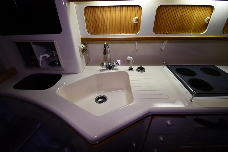 Slide: The Image of 1995 Sea Ray 440 Sundancer yacht kitchen with sink, stove, and wooden cabinets. - 36