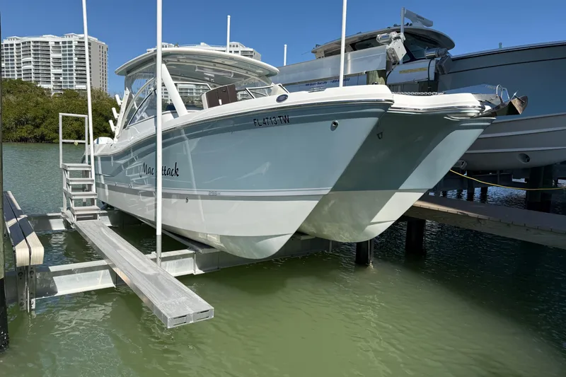 The Image of 2024 World Cat 296 DC boat docked on a lift, with modern buildings in the background. - 0