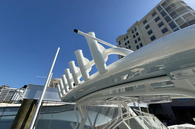 Slide: The Image of 2024 World Cat 296 DC boat with rod holders, docked near tall buildings under clear blue sky. - 21