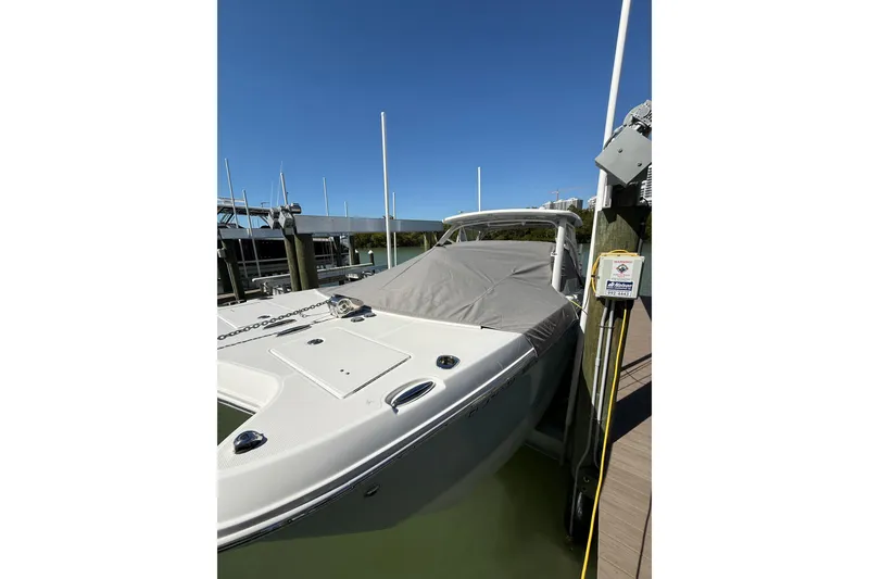 Slide: The Image of 2024 World Cat 296 DC boat docked with cover, under clear blue sky. - 27