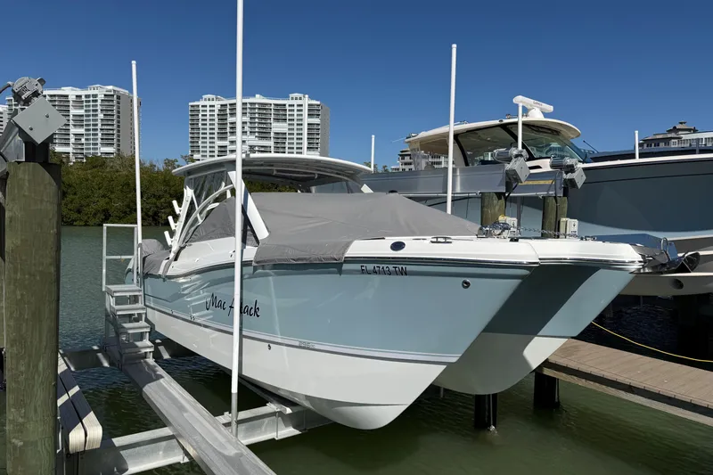 Slide: The Image of 2024 World Cat 296 DC boat docked with cover, cityscape in background. - 30