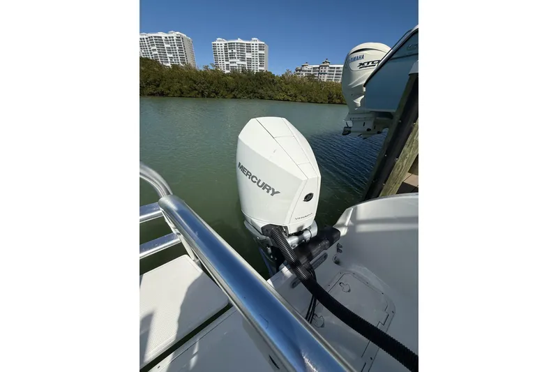 Slide: The Image of 2024 World Cat 296 DC boat with Mercury outboard engine, docked near waterfront buildings. - 5