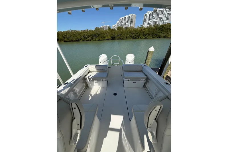 Slide: The Image of 2024 World Cat 296 DC boat interior with seating, docked by a scenic waterway. - 7