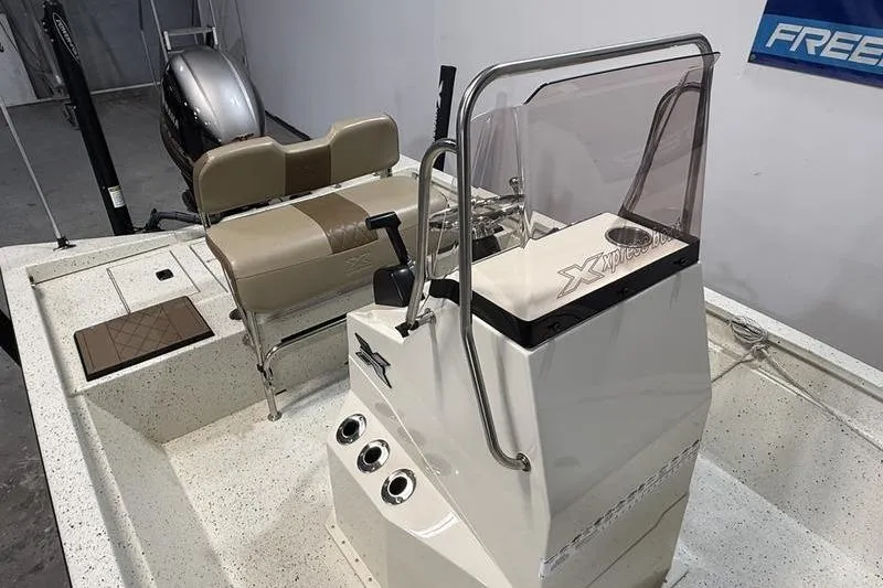 Slide: The Image of 2022 Express H190B boat interior with console, seating, and motor in a showroom. - 7
