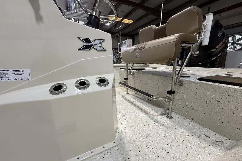 Slide: The Image of 2022 Express H190B boat interior with beige seating and control panel in a showroom. - 8