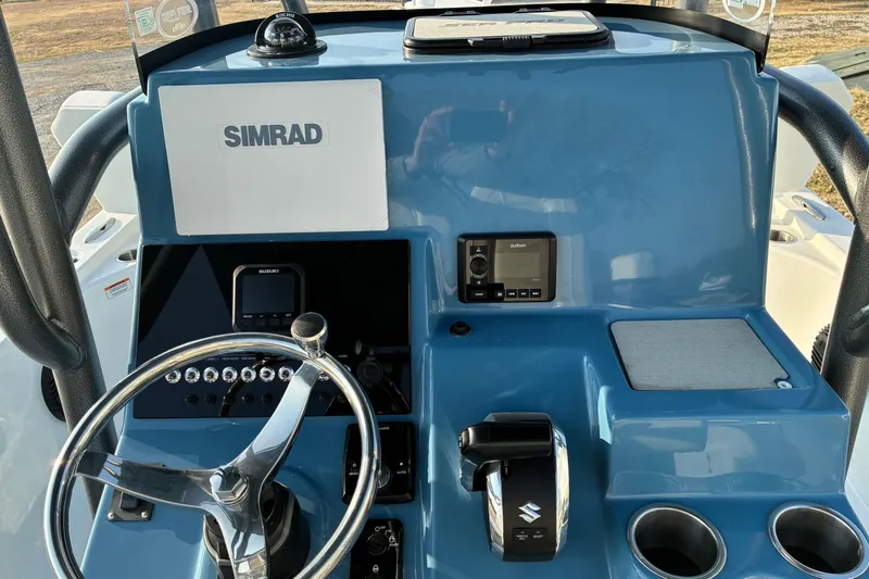 Slide: The Image of 2026 Sea Pro 250 Bay boat dashboard with Simrad electronics and Suzuki controls. - 14