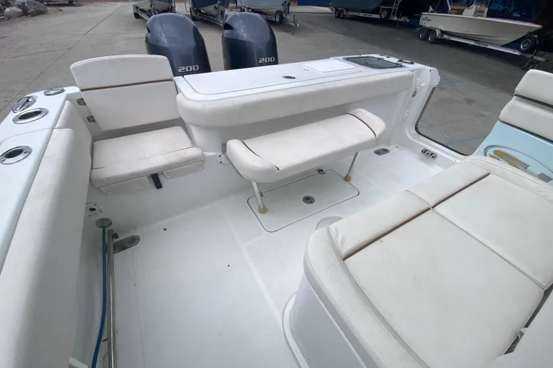 Slide: The Image of 2021 Sea Hunt Gamefish 27 Forward Seating boat interior with white cushioned seats and twin engines. - 28