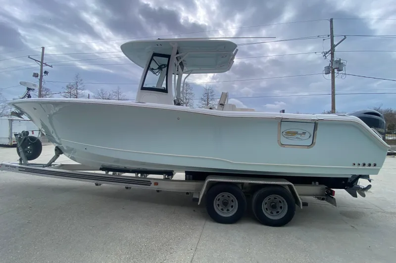 Slide: The Image of 2021 Sea Hunt Gamefish 27 Forward Seating boat on trailer under cloudy sky. - 6