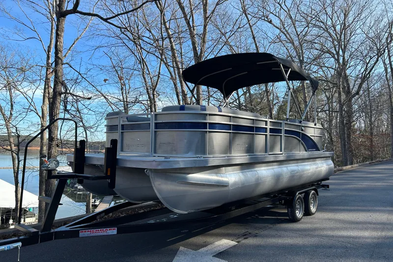 The Image of 2023 Bennington 22 SSRX pontoon boat on trailer, parked near a lake with trees. - 1