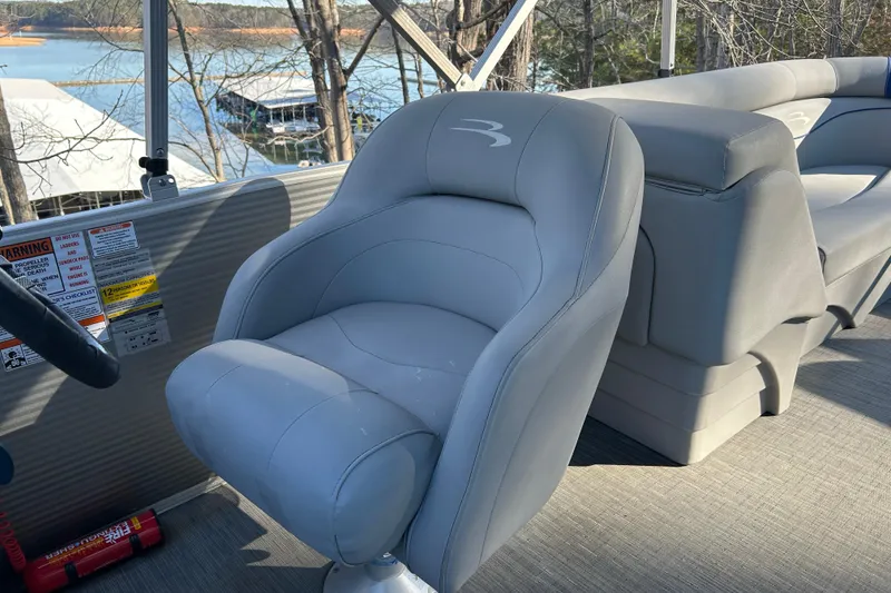 Slide: The Image of 2023 Bennington 22 SSRX boat interior with gray captain's chair and scenic lake view. - 11