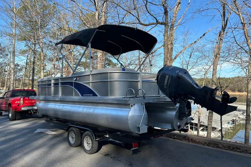 Slide: The Image of 2023 Bennington 22 SSRX pontoon boat on trailer, parked near a lake. - 3