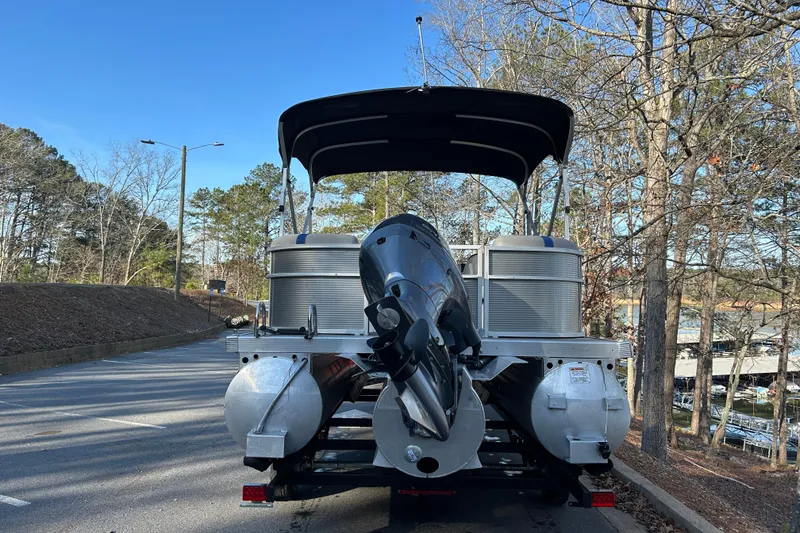 Slide: The Image of 2023 Bennington 22 SSRX pontoon boat on trailer, parked on a wooded road. - 4