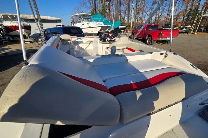 Slide: The Image of 2019 Starcraft MDX 211 O/B boat with red and white seating, parked outdoors. - 20