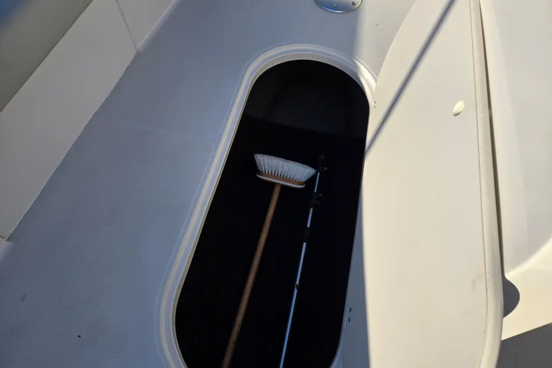 Slide: The Image of 2019 Starcraft MDX 211 O/B boat storage compartment with a broom inside. - 40
