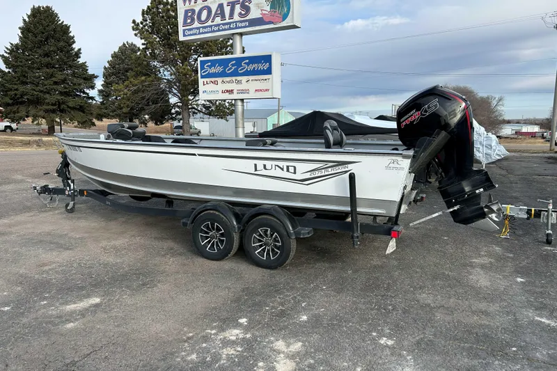 Slide: The Image of 2025 Lund 2075 Alaskan Tiller boat on trailer, parked outdoors near dealership. - 1