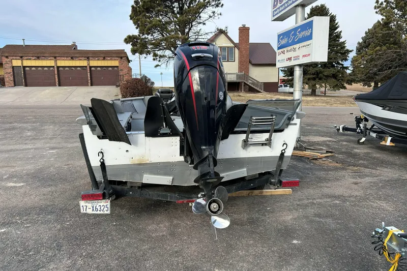 Slide: The Image of 2025 Lund 2075 Alaskan Tiller boat with outboard motor in a parking lot. - 2