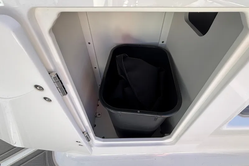 Slide: The Image of Storage compartment in 2026 Monterey Elite 27 OB boat with black container inside. - 17