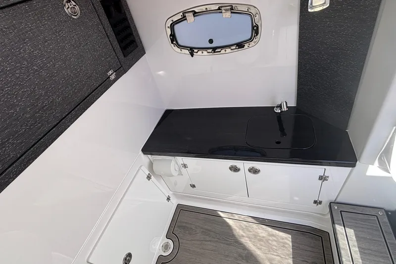 Slide: The Image of 2026 Monterey Elite 27 OB boat interior with sleek black countertop and compact sink. - 47
