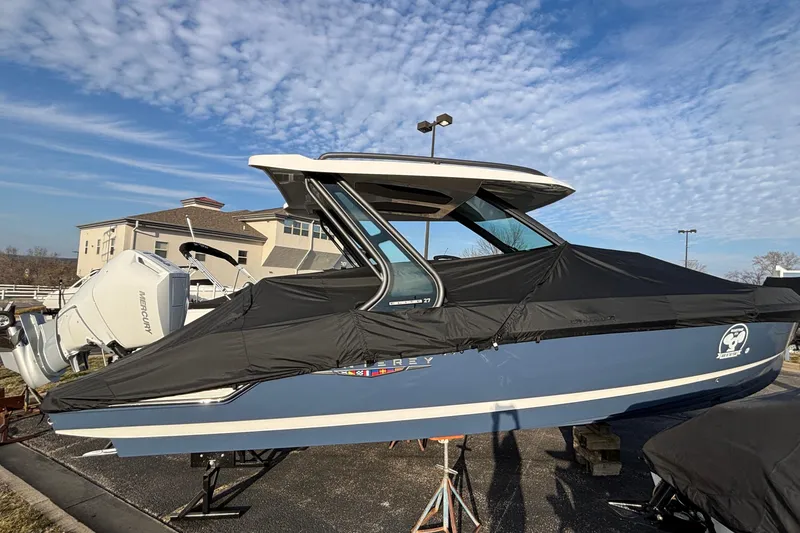 Slide: The Image of 2026 Monterey Elite 27 OB boat with cover, parked outdoors under a blue sky. - 5