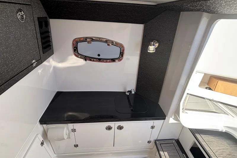 Slide: The Image of 2026 Monterey Elite 27 OB boat interior with sleek black countertop and modern fixtures. - 51