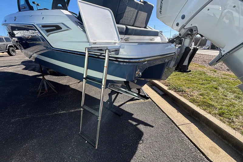 Slide: The Image of 2026 Monterey Elite 27 OB boat with ladder and outboard motor, parked on pavement. - 66