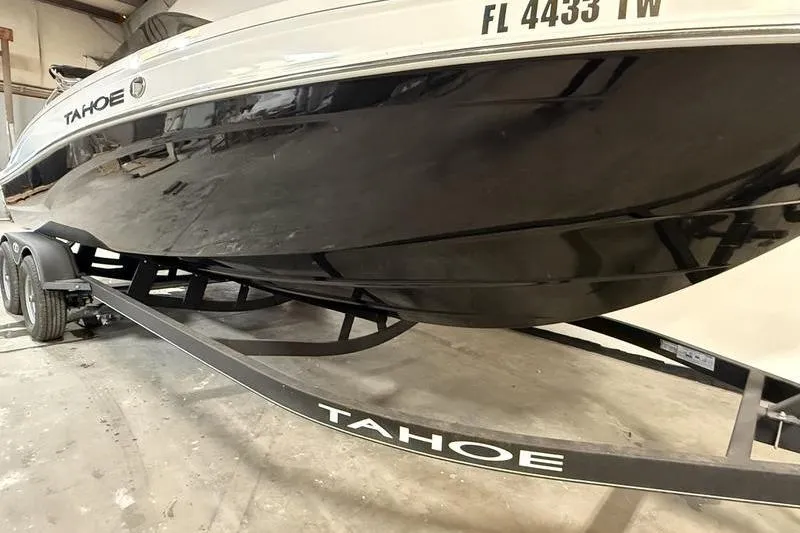 Slide: The Image of 2024 Tahoe T21 boat on trailer, black and white design, parked indoors. - 2