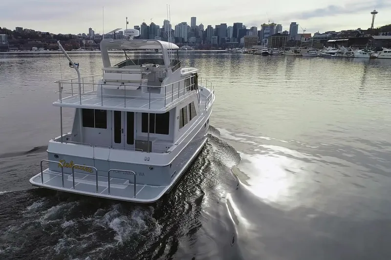 Slide: The Image of 2025 Helmsman Trawlers 46 Pilothouse cruising near city skyline on calm water. - 31