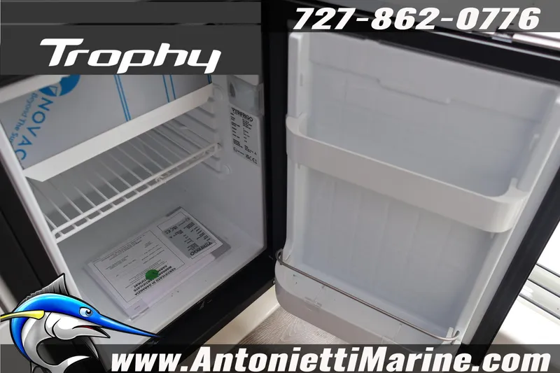Slide: The Image of Open refrigerator inside 2026 Bayliner Trophy T25 Explorer boat, featuring storage shelves. - 16