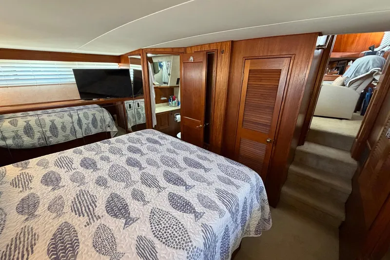 Slide: The Image of 1987 Viking 44 Motor Yacht bedroom with patterned bedding, wooden cabinetry, and a TV. - 57