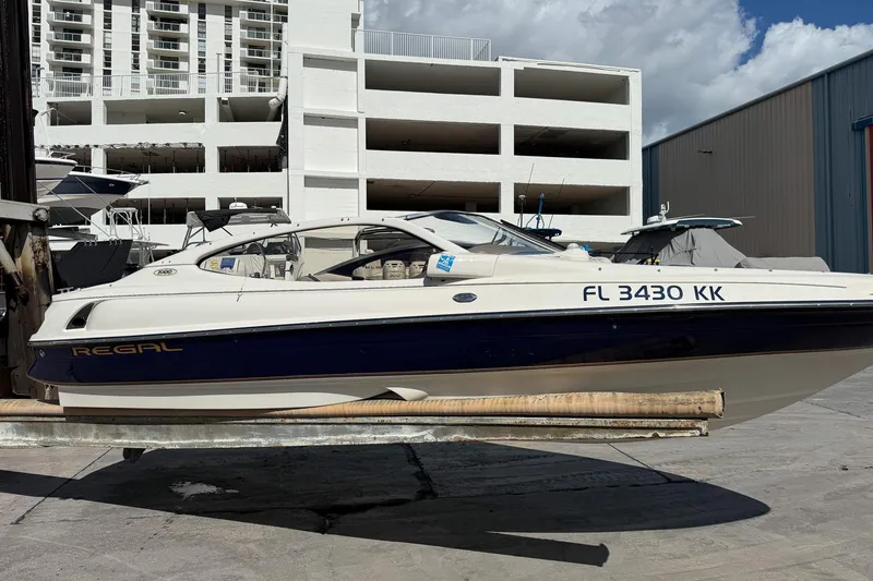 The Image of 1999 Regal 1900 LSR boat on lift, dockside with buildings in background. - 0