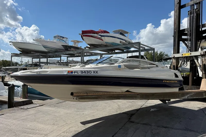 Slide: The Image of 1999 Regal 1900 LSR boat on lift at marina, surrounded by other boats. - 22