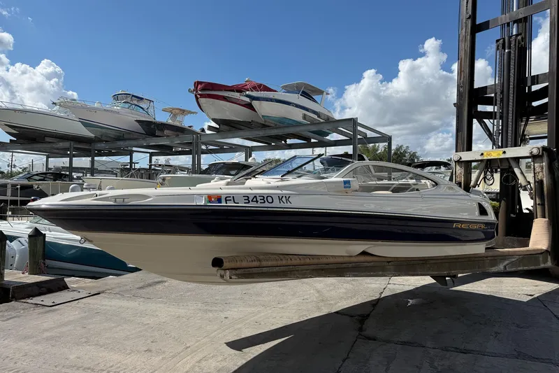 Slide: The Image of 1999 Regal 1900 LSR boat on forklift at marina, clear sky background. - 23