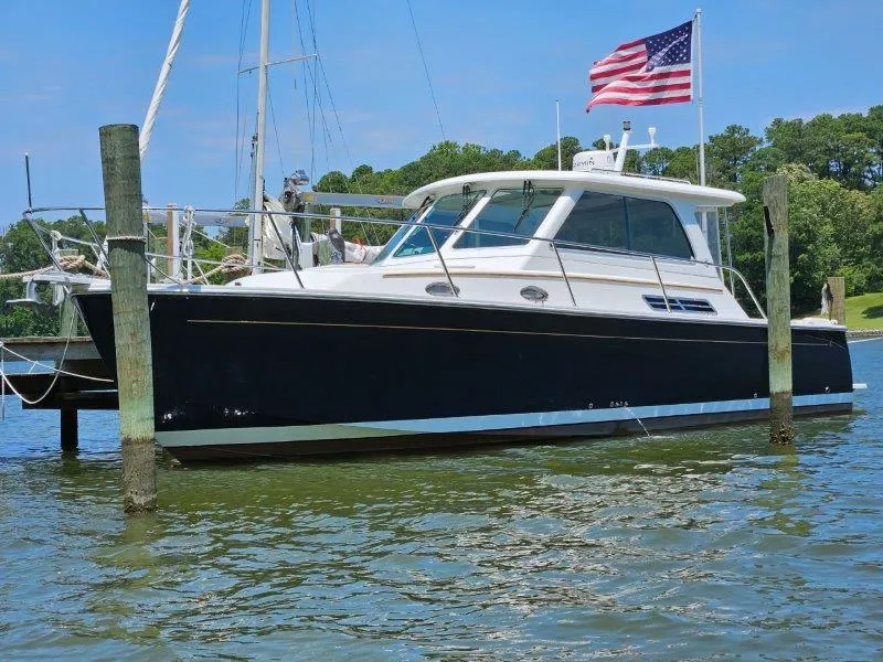 Slide: The Image of 2010 Back Cove 33 boat docked, American flag waving, calm water, clear sky. - 1