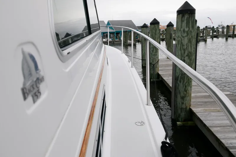 Slide: The Image of 2010 Back Cove 33 boat docked at a marina, side view with railing and logo. - 10