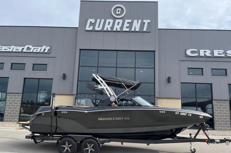 Slide: The Image of 2023 MasterCraft NXT24 boat on trailer outside dealership, showcasing sleek design. - 2