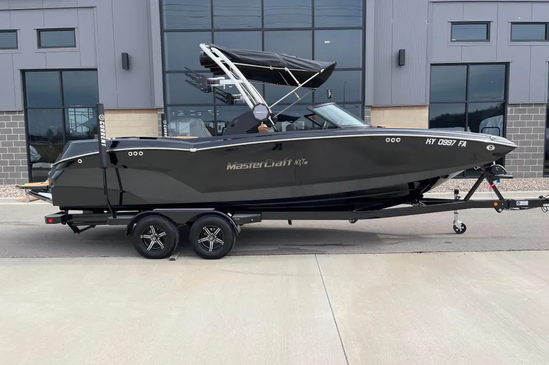 Slide: The Image of 2023 MasterCraft NXT24 boat on trailer, parked outside modern building. - 3