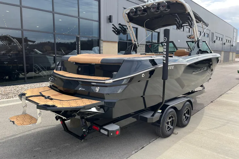 Slide: The Image of 2023 MasterCraft NXT24 boat on trailer, sleek black design, parked near modern building. - 4