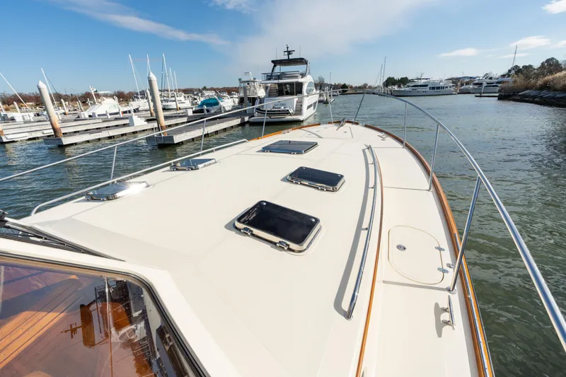 Slide: The Image of 2010 Hinckley Talaria 44 MKII Express yacht docked at a marina, showcasing sleek deck design. - 49