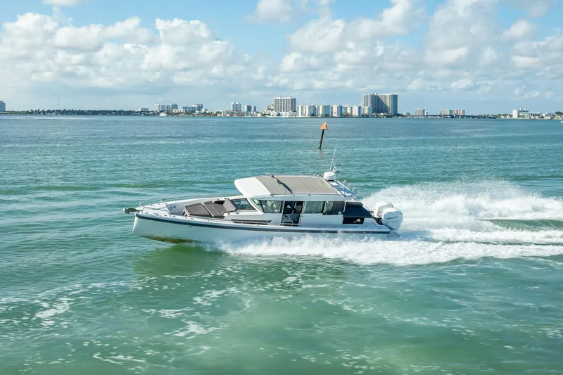 Slide: The Image of 2017 Axopar 37 XC Cross Cabin cruising on open water with city skyline backdrop. - 4