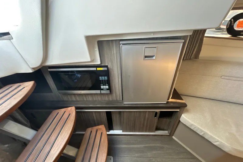 Slide: The Image of 2021 Sea Ray Sundancer 320 interior with microwave, mini fridge, and wooden steps. - 14