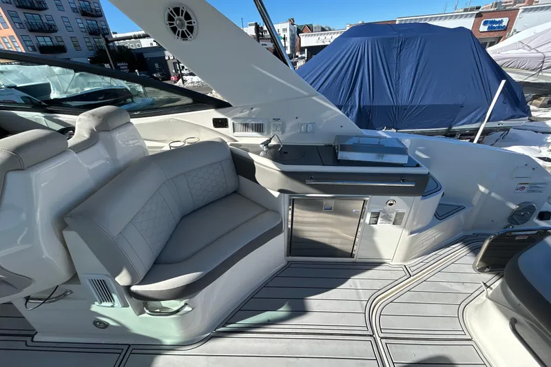 Slide: The Image of 2021 Sea Ray Sundancer 320 interior with seating and kitchenette, docked outdoors. - 5
