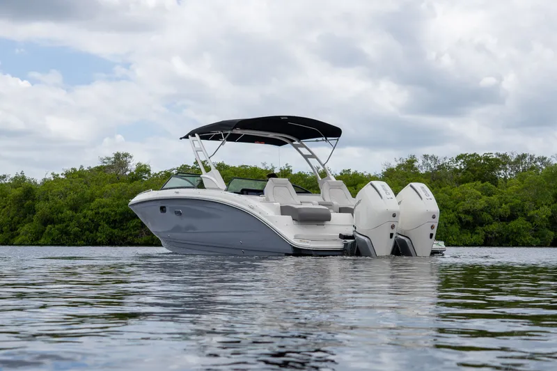 Slide: The Image of 2026 Sea Ray SDX 290 Outboard on calm water with green backdrop. - 23