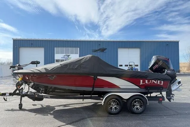 Slide: The Image of 2022 Lund 202 Pro-V GL boat with cover on trailer, parked outside blue building. - 32