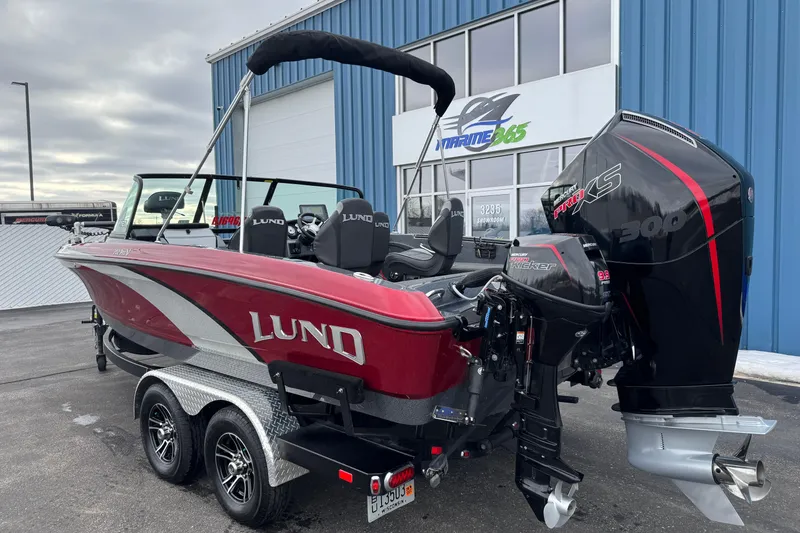 Slide: The Image of 2022 Lund 202 Pro-V GL boat with dual engines, parked outside a marine showroom. - 4