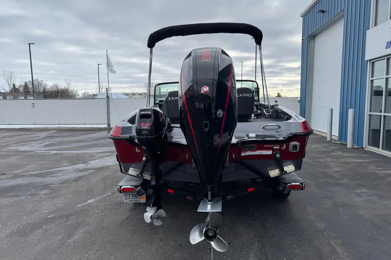 Slide: The Image of 2022 Lund 202 Pro-V GL boat with dual Mercury outboard motors, parked outside a blue building. - 6