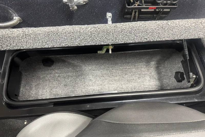 Slide: The Image of 2022 Lund 202 Pro-V GL boat storage compartment with carpeted interior and latch mechanism. - 9