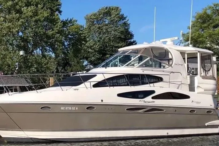 The Image of 2008 Cruisers Yachts 415 Express Motoryacht docked near lush trees. - 0